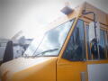 A yellow 2008 Freightliner MT45 Chassis with a large windshield a side mirror and a prominent light on the roof