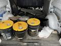 The interior of a 2018 Mercedes-Benz Metris van filled with four yellow-lidded black buckets along with various items including wood and other debris on the floor