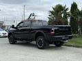 A black 2024 RAM 2500 truck with a prominent rear view showcasing its large tires and bold branding