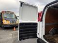 A 2022 GMC Savana cargo van with its rear door open, revealing a spacious interior with wooden flooring and black rubber lining on the sides