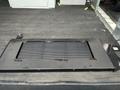 A black metal platform with a textured surface is positioned on a flat surface inside a vehicle, featuring a rectangular opening in the center.