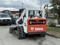 Rear view of a 2017 Bobcat T740 compact track loader with an orange and white body and visible tracks