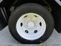 Close-up of a white wheel with a silver rim and eight lug nuts mounted on a large tire designed for a 2016 Isuzu NPR