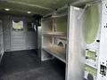 Interior view of a 2023 Ford Transit showing metal shelving units along the side walls with a smooth floor and insulated walls