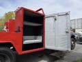 A 2013 Ford F-550 with an open storage compartment featuring a red exterior and metal shelves inside the compartment
