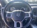 Steering wheel of a 2021 RAM 1500 with controls for audio and cruise settings visible along with the dashboard gauges behind it