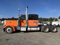 A 2009 Peterbilt Highway truck with a black and orange exterior featuring a prominent silver exhaust stack and large rear tires