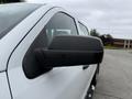 Side mirror of a white 2016 GMC Sierra 1500 showing a streamlined design and a black casing