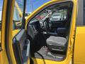 A yellow 2015 RAM 1500 pickup truck with a gray interior and a spacious front cabin featuring a steering wheel and dashboard visible from the open driver's side door