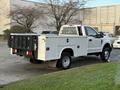 A 2018 Ford F-350 pickup truck with a white exterior and a flatbed design featuring a tool compartment in the rear and a perforated metal frame above the cab