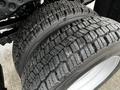 Close-up of a pair of large off-road tires with deep tread patterns mounted on a 2008 Ford F-450 SD
