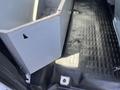 Interior view of a 2013 Ford F-250 SD showing a gray storage compartment with a textured rubber floor mat beneath it