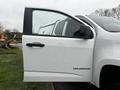 A 2018 Chevrolet Colorado with its driver's side door open showcasing the white exterior and Colorado badge