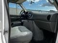 Interior view of a 2004 Ford Econoline featuring grey leather seats and a dashboard with various controls and a steering wheel visible