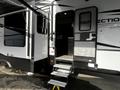 A 2021 Grand Design Recreational 311BHS travel trailer featuring an exterior door with steps leading up to it and an awning extended over the entry area