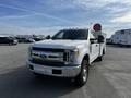 A white 2017 Ford F-350 Super Duty truck with a large red satellite dish mounted on the bed