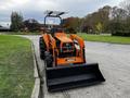 A 2001 Agco ST40 tractor with an orange body and black tires equipped with a front loader bucket positioned in a gravel area