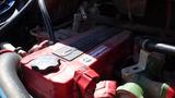 Red engine cover of a 2014 Freightliner Thomas bus diesel with various hoses and connectors visible in the foreground