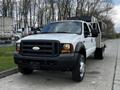 A 2007 Ford F-550 truck with a white body and black grille facing forward parking on a concrete surface