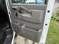 The interior door panel of a 2021 Chevrolet Express featuring a handle a door lock mechanism and storage compartments