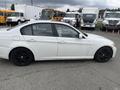 A white 2011 BMW 3-Series parked with a profile view showing dark wheels and a clean design