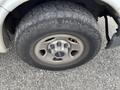 A close-up of a 2014 GMC Savana tire showcasing a rugged tread pattern and a silver wheel with a prominent GMC logo in the center