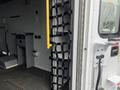 A 2016 Chevrolet Express van interior featuring a black cargo netting system attached to the wall with a yellow grab bar visible on the side