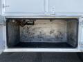 An empty storage compartment of a 2004 Freightliner M2 showing metal walls and no items inside
