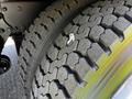 Close-up of a large truck tire with a detailed tread pattern showcasing a piece of debris embedded in the rubber surface