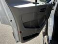 The interior door panel of a 2023 Ford Transit featuring a textured gray surface with a handle and storage compartment