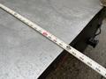 A close-up of a metal surface with a measuring tape laid across it showing measurements in inches
