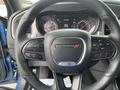 The steering wheel of a 2022 Dodge Charger featuring controls for audio and cruise settings with the Dodge emblem in the center