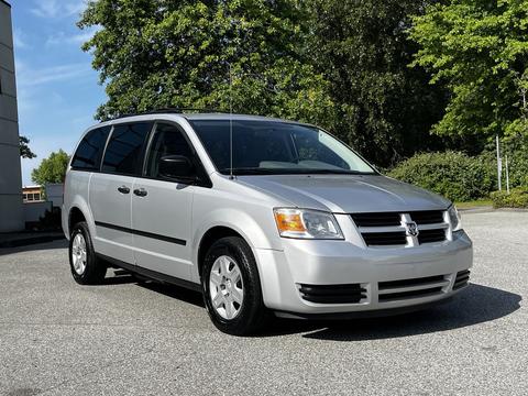A silver 2009 Dodge Grand Caravan parked with a sleek design featuring a front grille and large windows