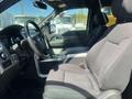 Interior view of a 2014 Ford F-150 showing the driver's seat and steering wheel with a focus on the dashboard controls and center console