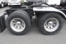 A 2015 Kenworth T660 showing the rear wheels with silver rims and large black tires mounted on a flatbed truck chassis