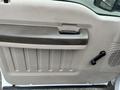 Interior door panel of a 2010 Ford F-250 SD featuring a handle and manual window crank with textured surfaces and some dirt or wear visible