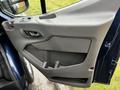 The interior door panel of a 2020 Ford Transit featuring a handle a storage pocket and control buttons