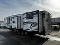 A 2021 Grand Design Recreational 311BHS travel trailer featuring a sleek white exterior with black and gray accents and multiple slide-outs