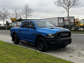 A blue 2021 RAM 1500 Classic pickup truck with a black grille and accents parked on the side of a road