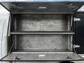 A 2007 Ford F-550 with open storage compartments featuring two shelves made of metal with chain supports