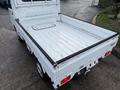 A 2009 Suzuki Carry with a flatbed design featuring a clean white exterior and an empty cargo area