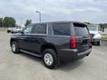 A 2016 Chevrolet Tahoe in black with chrome wheels parked at an angle showing the rear and side of the vehicle