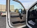 Interior view of the driver side door of a 2018 Ford F-350 featuring beige and black paneling with a truck handle and speaker visible