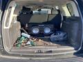 The interior of a 2007 Cadillac Escalade with an open trunk showing a large audio speaker box and various items like tools and a paper towel inside