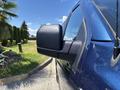 Side view mirror of a blue 2015 Ford F-150 with a shiny finish