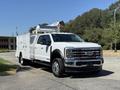 A white 2024 Ford F-550 Super Duty truck featuring a service body and a mounted ladder on top