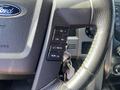 Close-up of the steering wheel controls of a 2014 Ford F-150 featuring buttons for volume media and a confirmation option