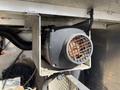 A close-up view of a ventilation fan or blower unit designed for use in a vehicle or machinery with a metal grille cover and electrical connections