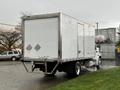A 2017 Freightliner M2 106 box truck with a white exterior and rear cargo door displaying hazardous material symbols