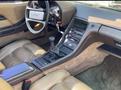 Interior of a 1983 Porsche 928 featuring brown leather seats a central console with controls a gear shifter and a steering wheel with a sporty design